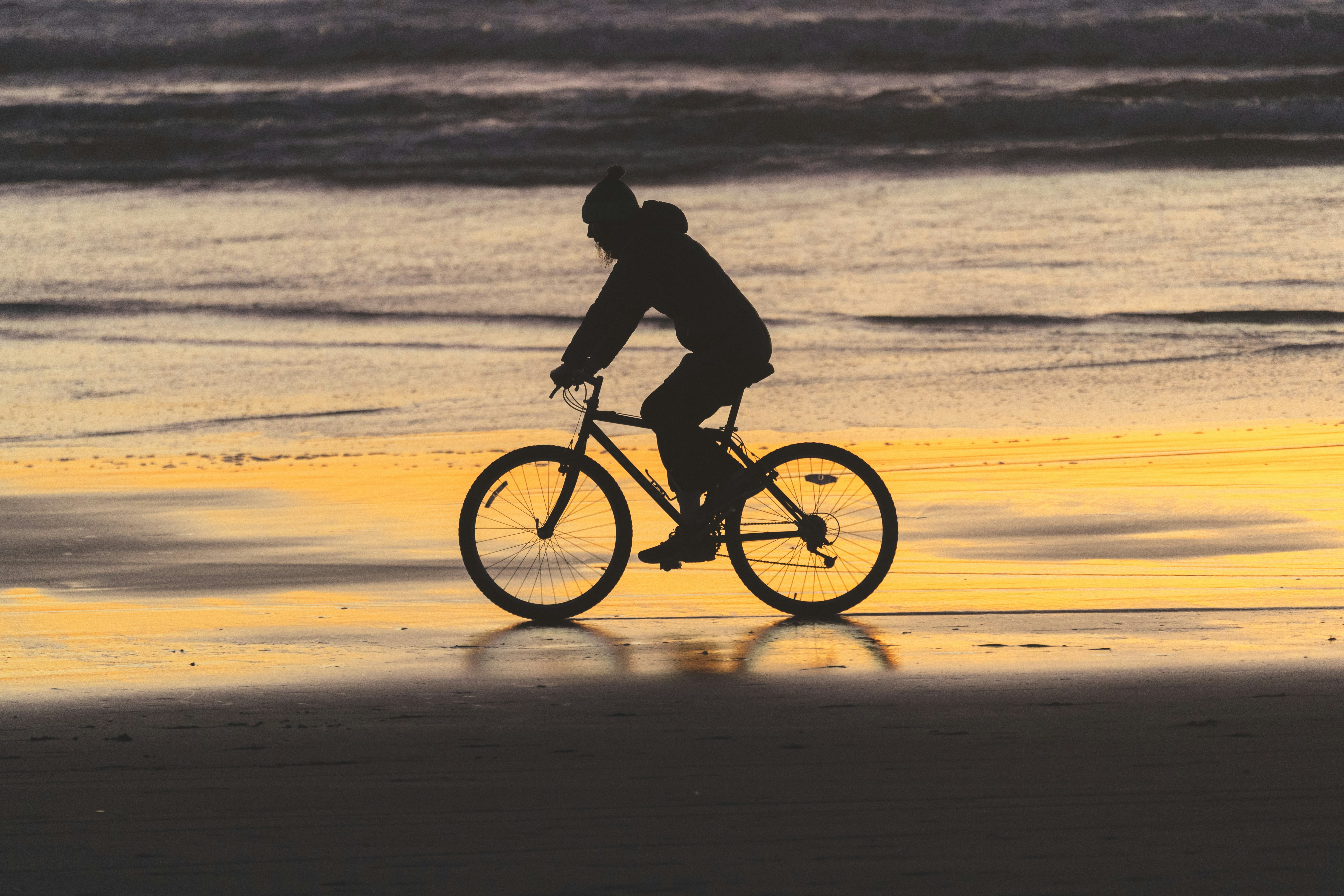 man riding bicycle on beach during daytime